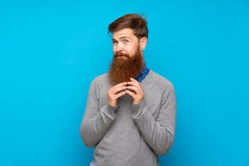 Redhead man with long beard over isolated blue background scheming something