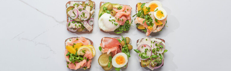 panoramic shot of fresh smorrebrod sandwiches on white marble surface