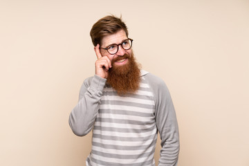 Redhead man with long beard over isolated background with glasses
