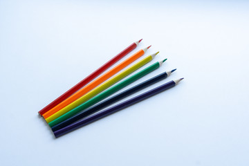 Fototapeta premium Set of six sharp rainbow-colored pencils except blue, from top view on a white background. Concept of creativity. Art supplies. Minimalism. Childhood. LGBT.