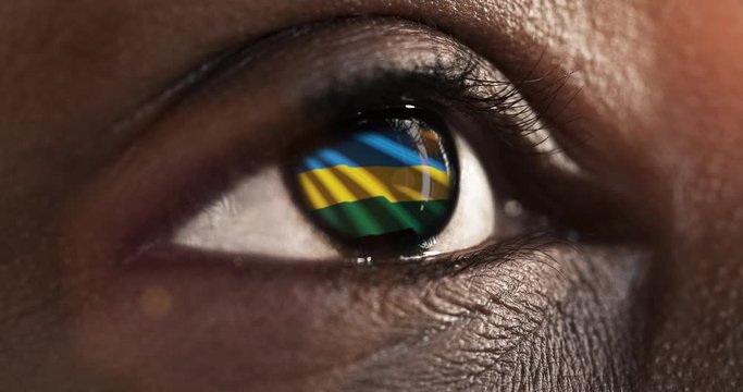 Woman black eye in close up with the flag of Rwanda in iris with wind motion. video concept