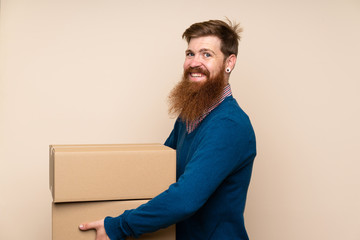 Redhead man with long beard over isolated background holding a box to move it to another site