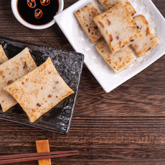 Delicious turnip cake, Chinese traditional radish cake in restaurant with soy sauce for new year's dishes, close up, copy space, top view, flat lay.