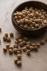 chickpeas scattered from bowl on beige wooden table