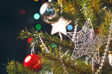 Beautiful Christmas decor concept, bauble hanging on the Christmas tree with sparkling light spot, blurry dark black background, macro detail, close up.