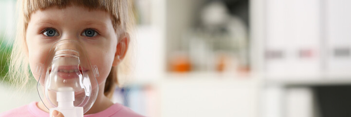 Little girl breathing with inhaler at doctor office