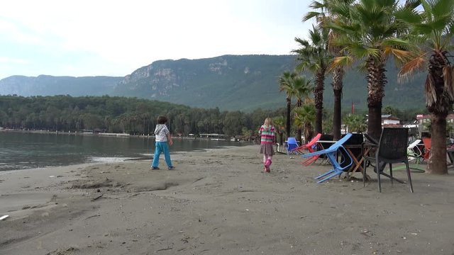Akyaka, Mugla, Turkey - 12th of November 2019: 4K Children collect findings on the beach after rain
