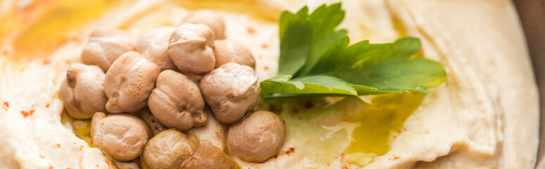 close up view of delicious hummus with chickpeas in bowl, panoramic shot