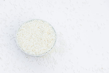 Milled rice in a cup and milled rice spread on a white ground