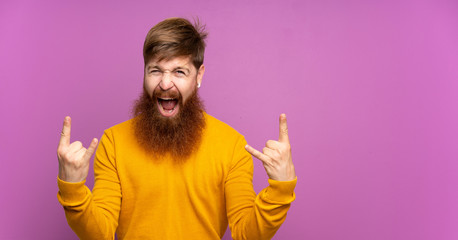 Redhead man with long beard over isolated purple background making rock gesture - obrazy, fototapety, plakaty