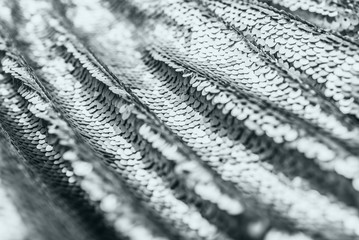 Grey shiny fabric with sequins, abstract background.