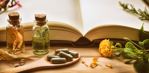 Traditional medicine with plants and book on the table detail