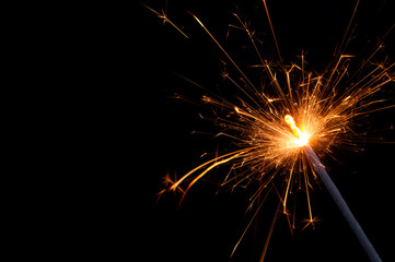 Burning firework sparkler on black background with room for text