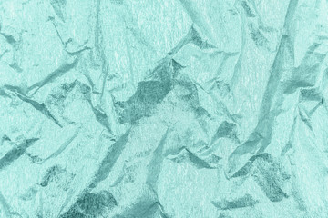 Crumpled toned mint green wrapping paper with shiny effect.