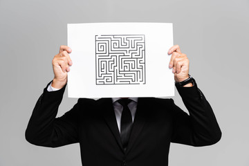 businessman obscuring face with paper with labyrinth isolated on grey