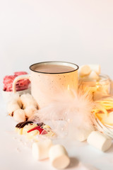Hot cocoa with marshmallows and candles on a white background. New Year composition with white christmas tree decorations. Chocolate snowman.
