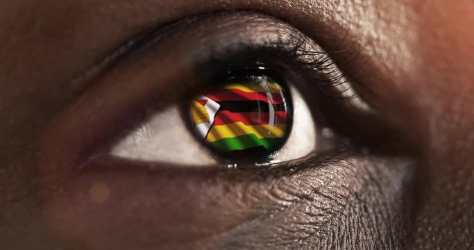 Woman black eye in close up with the flag of Zimbabwe in iris with wind motion. video concept