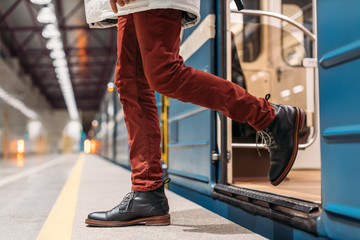 Attractive man in black shoes, burgundy pants and white jacket gets out of subway wagon. Male...