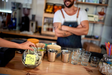 Woman is putting one dollar bill into a glass bowl