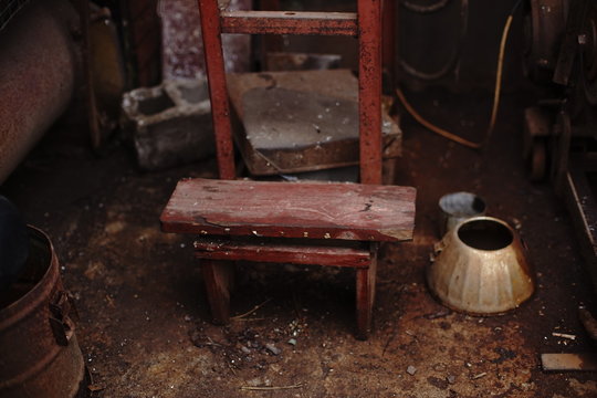 homemade chair and household items on a dirty floor.