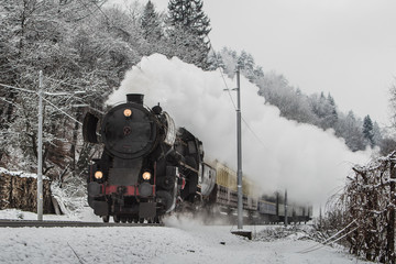 Christmas steam train on a gray winter day rushing towards camera and letting off steam