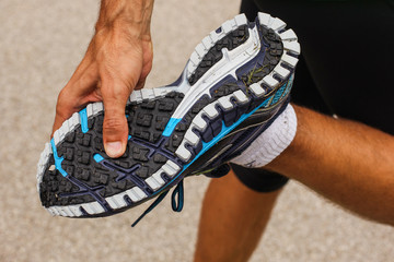 Hand of a man seen checking the thread on sneakers or sports running shoes