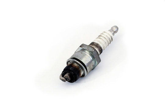 Worn and dirty spark plug of a car, isolated on white surface