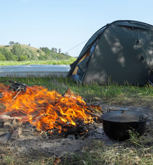 Campfire, cauldron and tent near the river