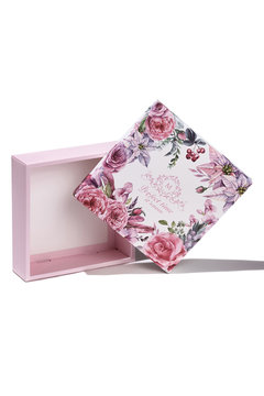 Subject shot of a white gift box with a white bottom and a lid decorated with colorful floral tropic print, design with letters and a pleasant text: "Perfect time it's now."