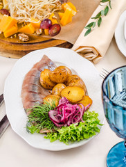 Served for holiday banquet restaurant table with canape with salted herring fish with potatoes slices and red onion, pickles, cucumber, snack, salads, cutlery, wine and water glasses. Russian food 