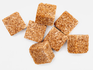 Lumps (cubes) of brown sugar (cane). Caramel brown color. Isolated on white background. Top view.