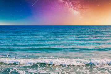 Night sky, milky way galaxy stars and space with sea or ocean and waves at the beach.