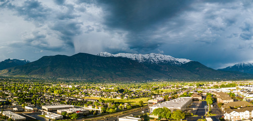 Storm in the snowy mountains and a city in the sun - obrazy, fototapety, plakaty