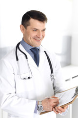 Doctor man using clipboard for filling up medication history records. Perfect medical service in clinic. Physician at work in hospital. Medicine and healthcare concepts