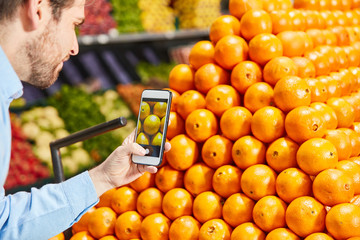 Kunde mit Smartphone App in der Obstabteilung