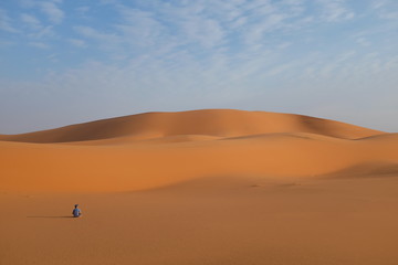 Fototapeta na wymiar A man sitting quietly on a vast desert landscape doing meditation and relaxation
