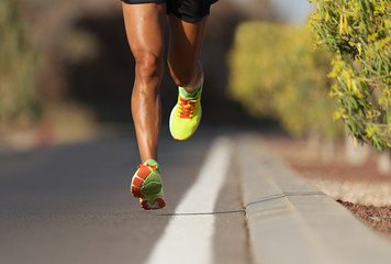 Fast strong runner feet running on asphalt road close up in sport shoe