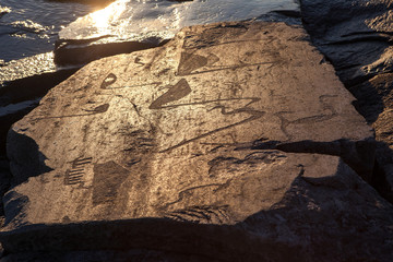 ancient rock carvings petroglyphs on the shore of Onega Lake carved on a granite plate . Age of...