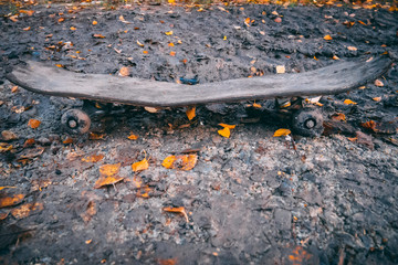 kaputtes Skateboard mit Blättern auf Schlamm