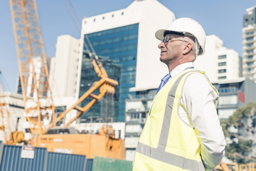 Senior foreman in glasses doing his job at building area on sunny day