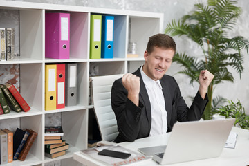 happy handsome man manager sitting in winning position after successful negotiations at his working...