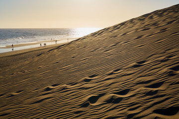 Sandberge von der Sahara - Dünenlandschaft am Strand von Gran Canaria mit den vulkanischen Bergen...