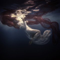 Woman in a beautiful dress swims underwater