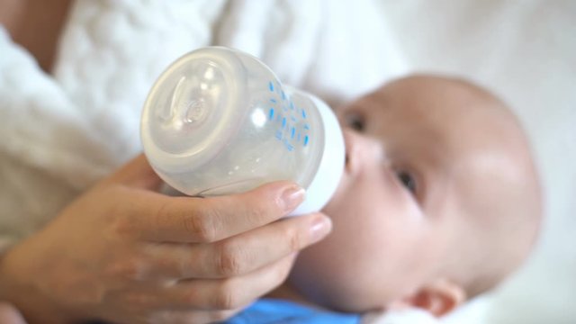 4K, Close-up Mother's hand holds a bottle and feeds the baby