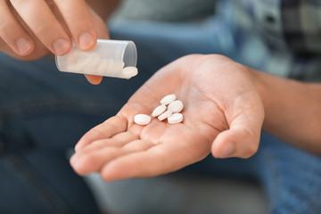 Man with pills at home, closeup