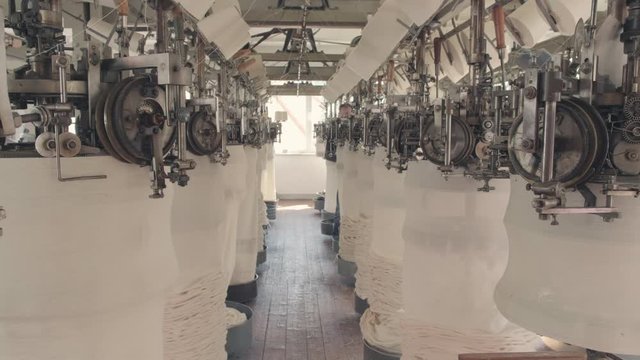 Workers working at a circular knitting machine in knitting factory
