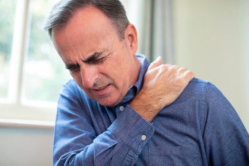 Mature Man Suffering With Trapped Nerve In Shoulder At Home