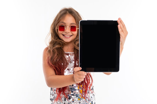 Little pretty caucasian girl shows a big tablet, picture isolated on white background