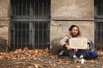 Poor homeless man holding cardboard with text HELP outdoors