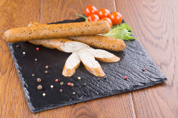 pork sausages with spices  сherry tomatoes and herbs on a slate board